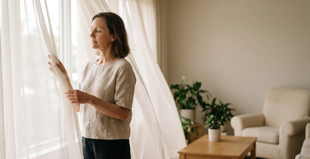 Personne debout sereinement dans un intérieur lumineux, entourée de voilages semi-transparents évoquant les expositions allergéniques multiples du quotidien