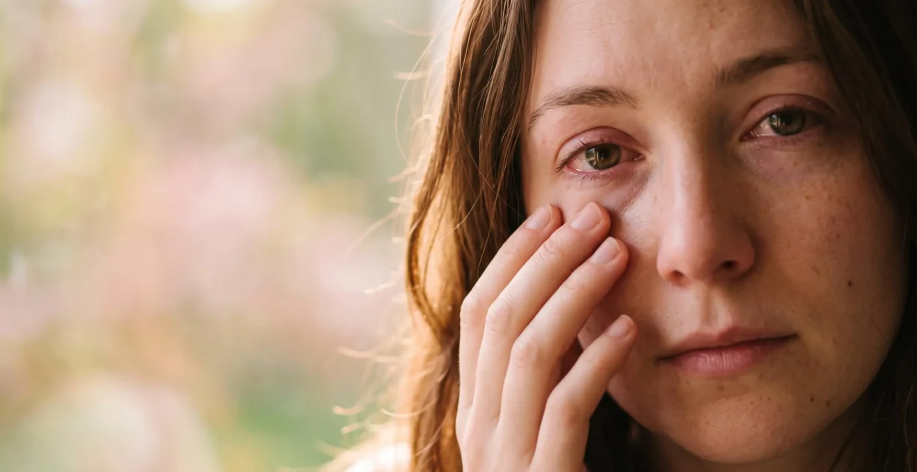 Portrait rapproché d'une personne retenant son geste de se frotter l'œil, illustrant la maîtrise face aux démangeaisons allergiques